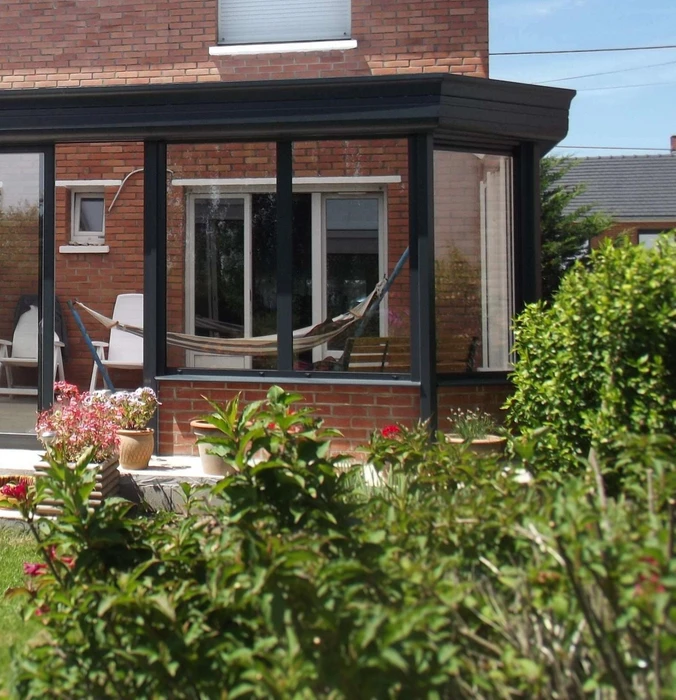 Véranda moderne attenante à maison en brique rouge, structure aluminium anthracite, grandes baies vitrées coulissantes