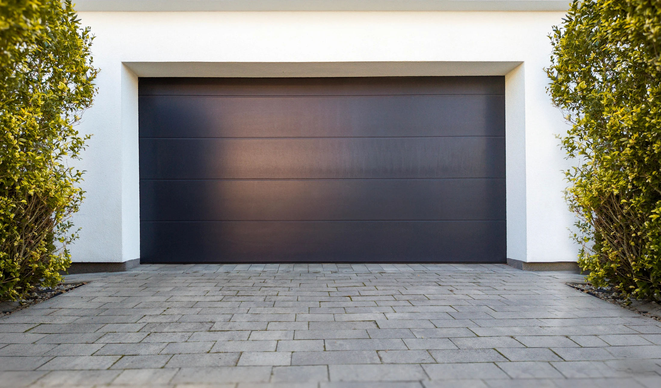 Entrée moderne de maison contemporaine avec porte de garage sectionnelle gris anthracite et porte d'entrée assortie