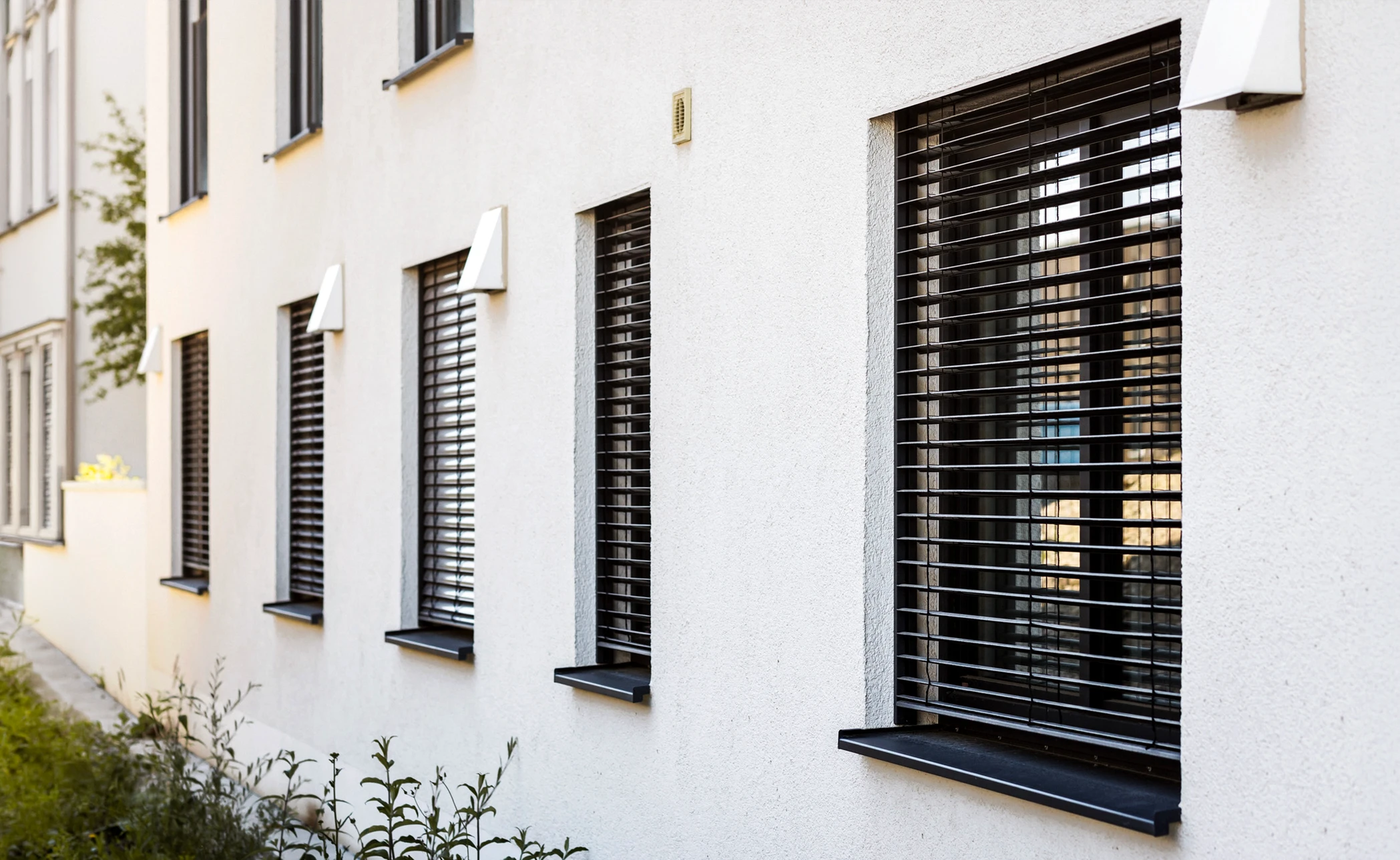 Façade d'immeuble résidentiel moderne avec balcons équipés de garde-corps métalliques et portes-fenêtres à encadrements jaunes