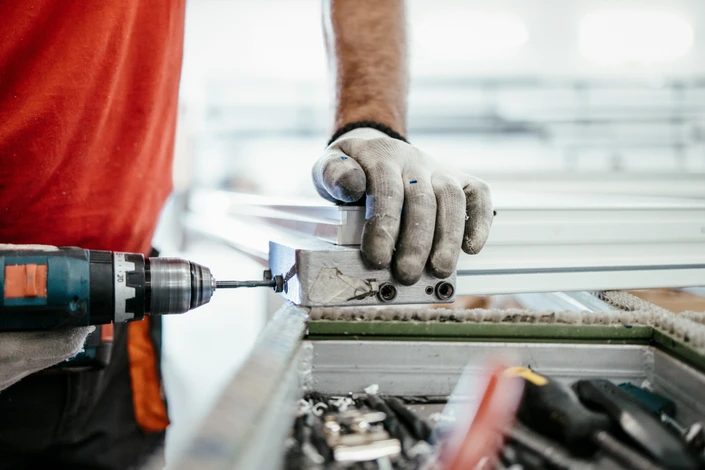 Artisan menuisier travaillant dans son atelier, manipulant une planche de bois sur établi